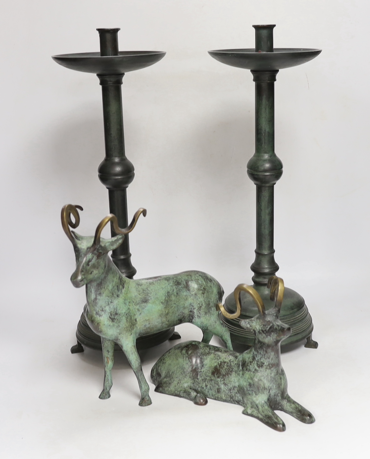 A pair of bronze candlesticks, 45.5cm, and a pair of stags, all with green patina
